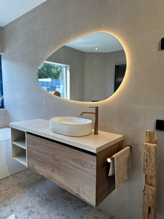 Beige badkamer met vrijstaand bad en verlichte spiegel in de showroom van Baderie Almere